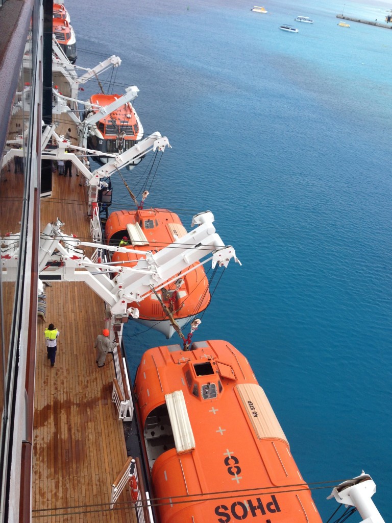 Lifeboats being lowered as part of a crew drill while in port.