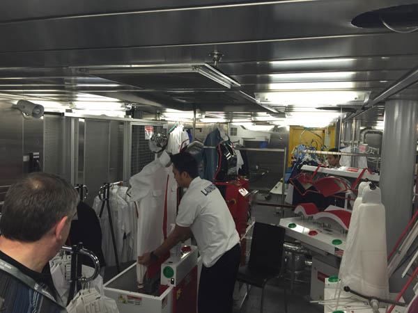 A worker in the laundry on Quantum of the Seas shows the machines that presses a shirt in seconds