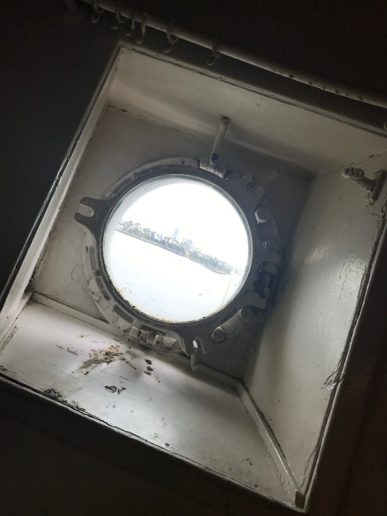 A porthole that could use a little preventative maintenance in the isolation ward exhibit on the Queen Mary