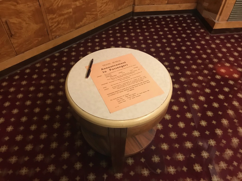 A table with a brochure in the Travel Bureau on the Queen Mary