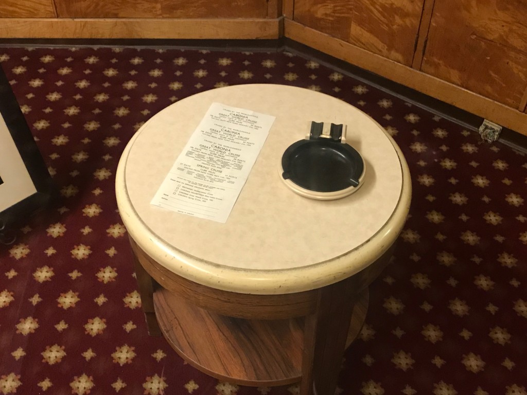 A table with a brochure in the Travel Bureau on the Queen Mary - notice the ash tray!