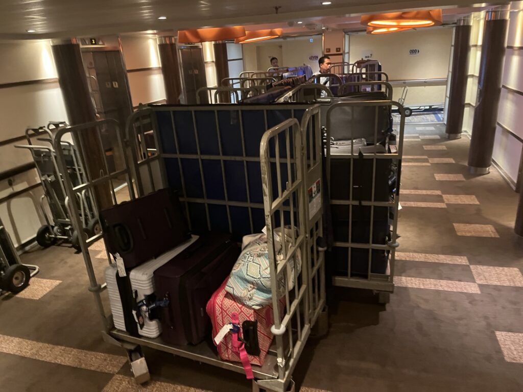 Crew members collecting luggage to be taken off the ship for debarkation