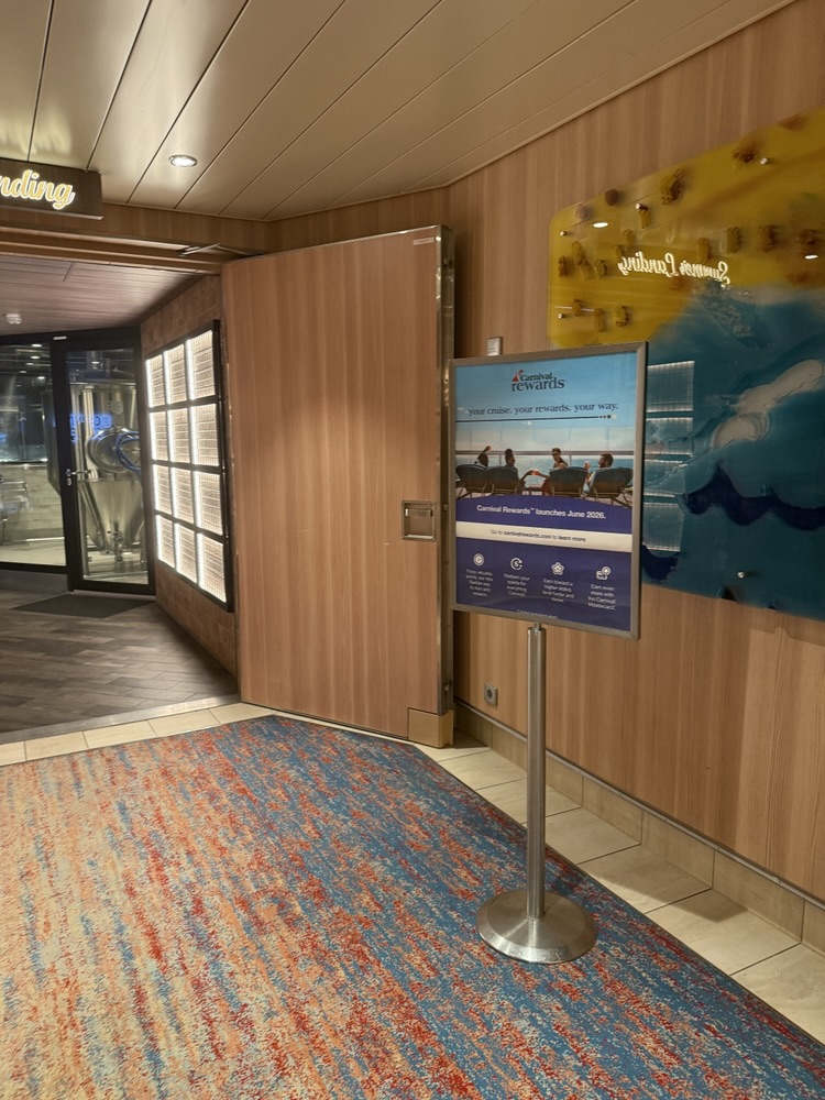 A sign where a crew member was stationed at a podium to answer questions about the Carnival Rewards program
